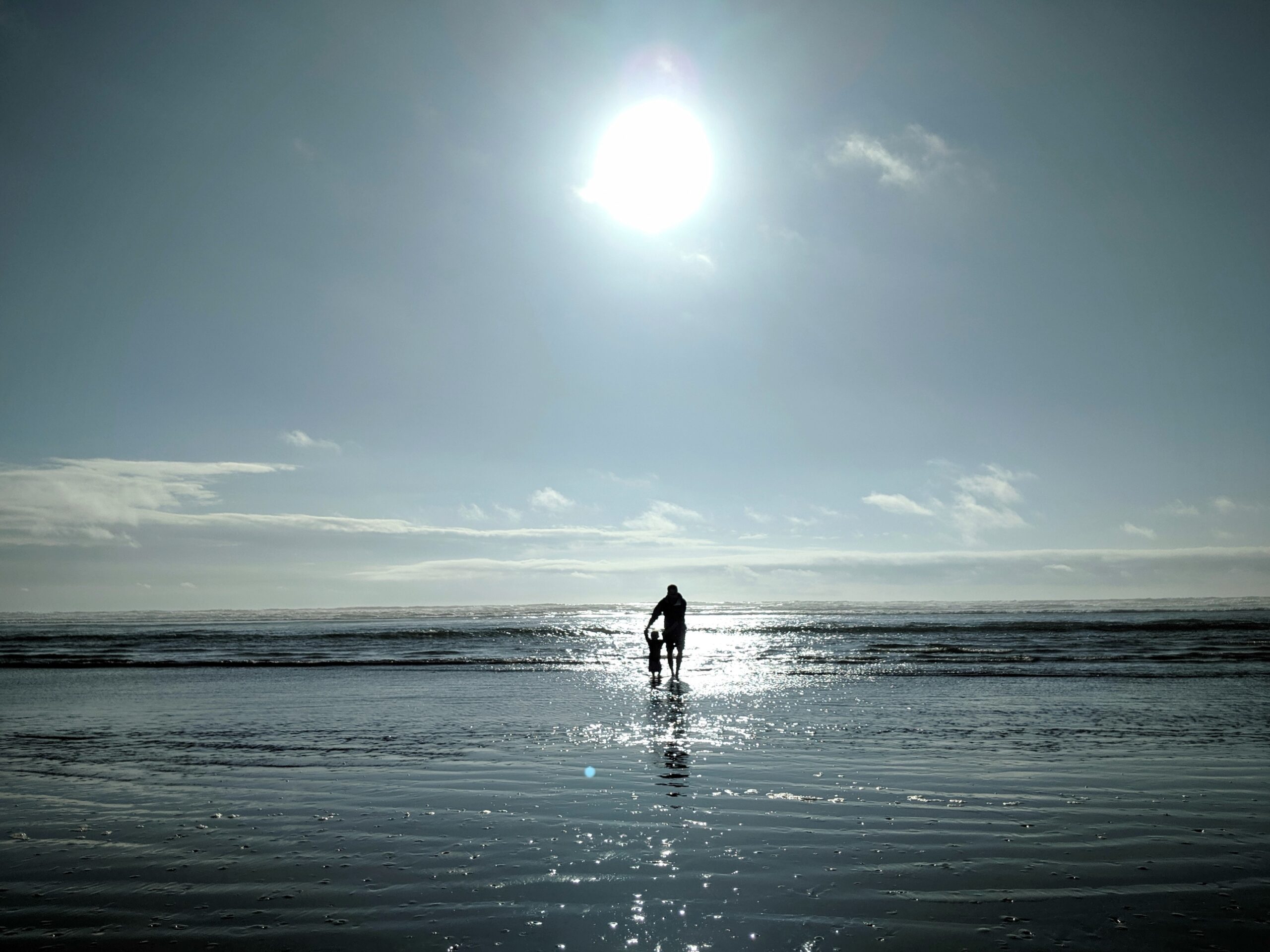 man and toddler walking on seashore
