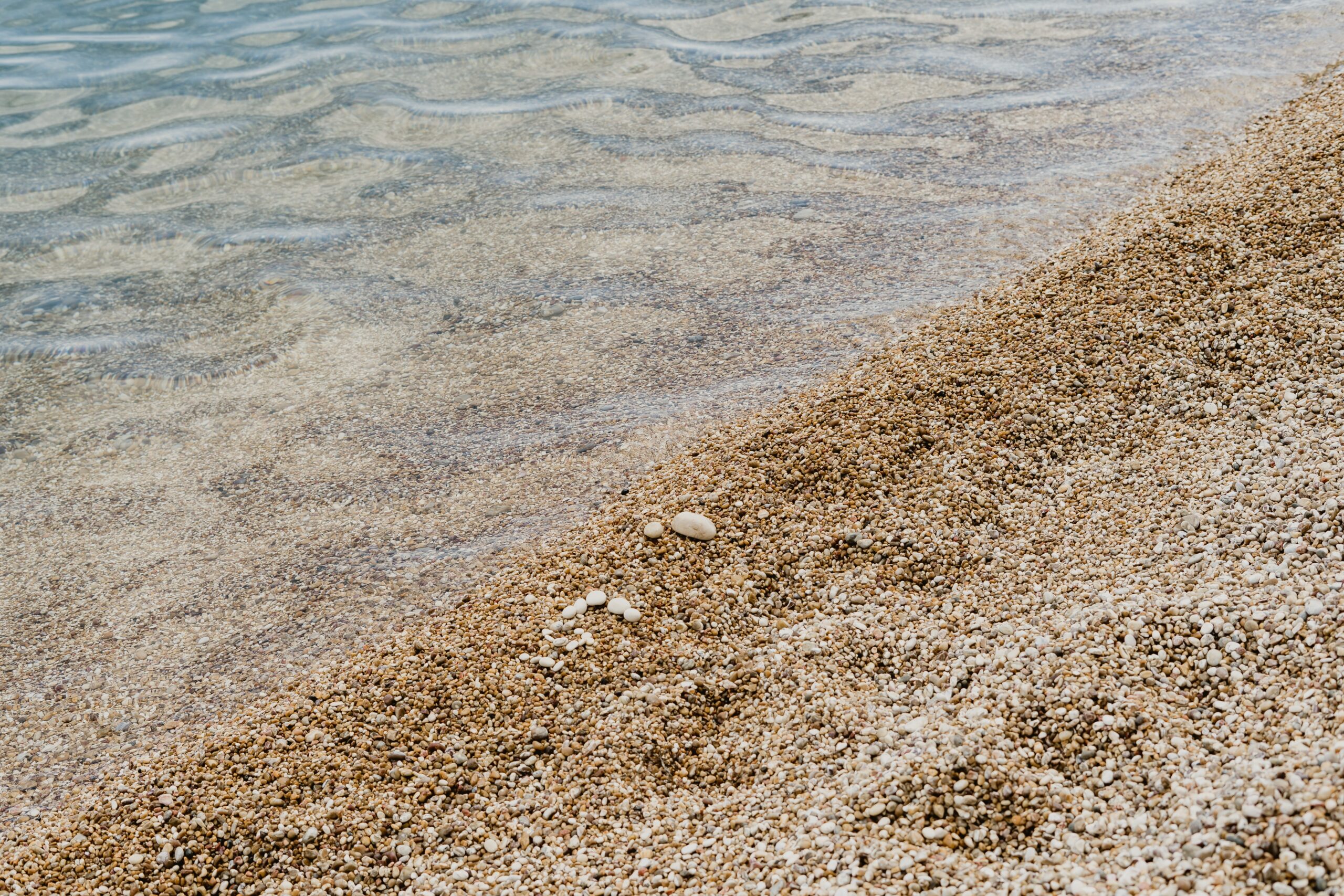 Gentle waves lapping over small pebbles at a beach called Vignanotica in Puglia, Italy