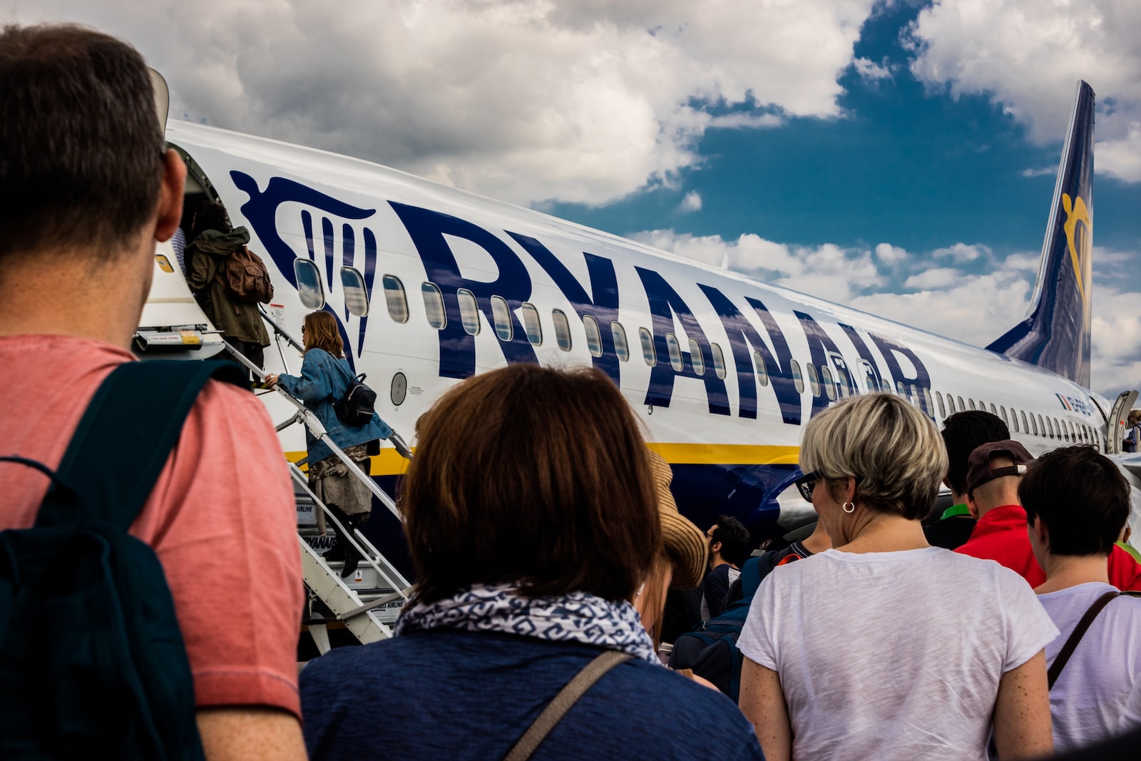 people sitting on chair near blue and white airplane under white clouds during daytime