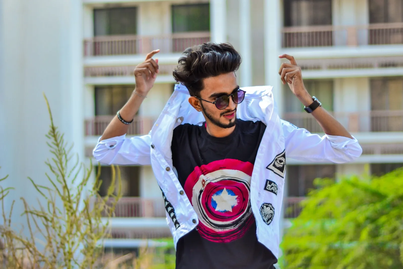 man in black shirt with white jacket standing near plants