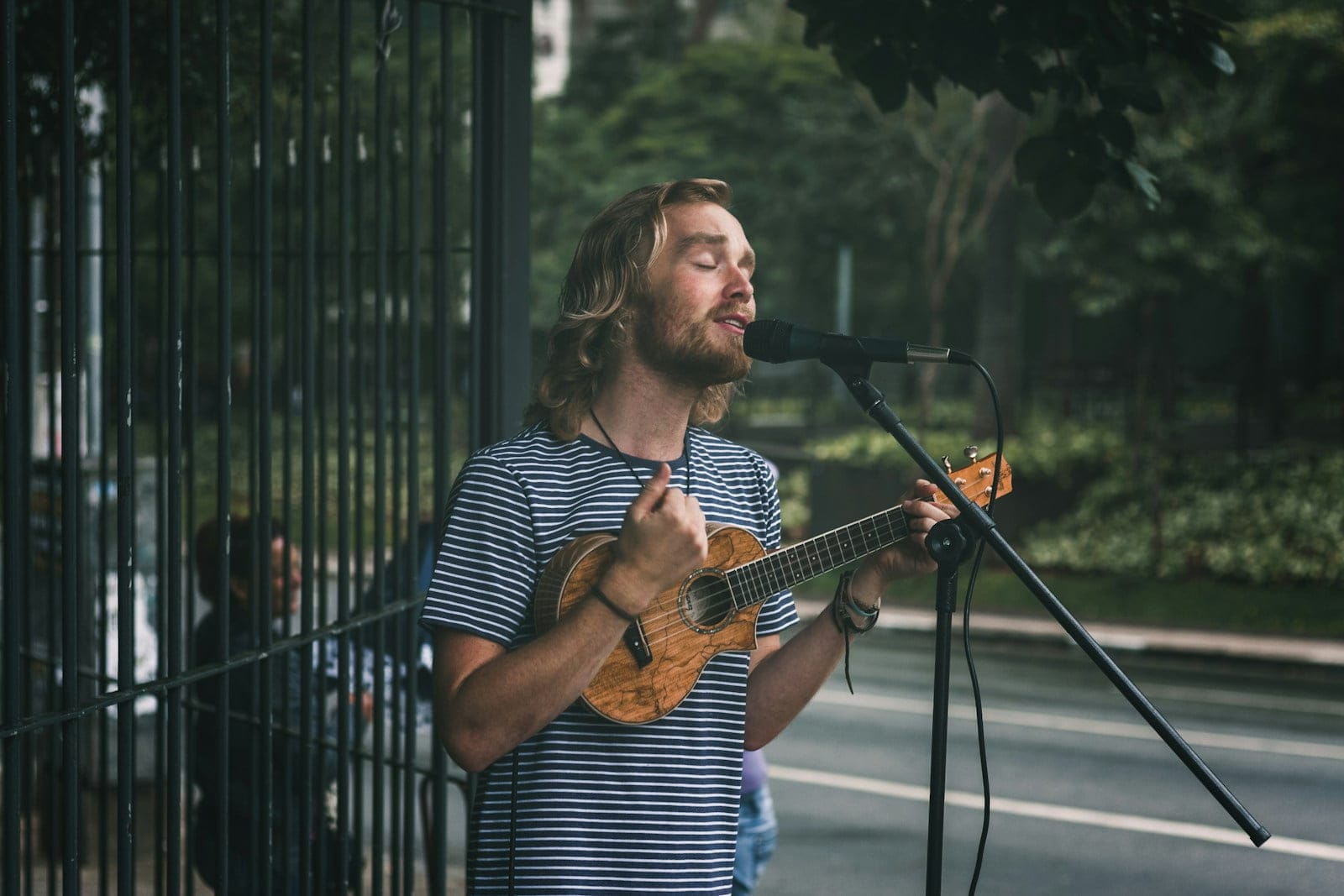 man holding ukulele standing near grills