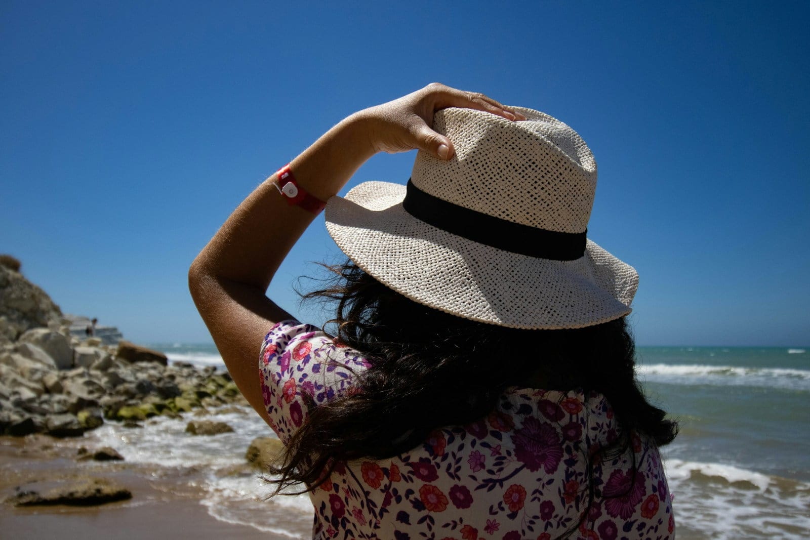 a woman wearing a hat standing on a beach
