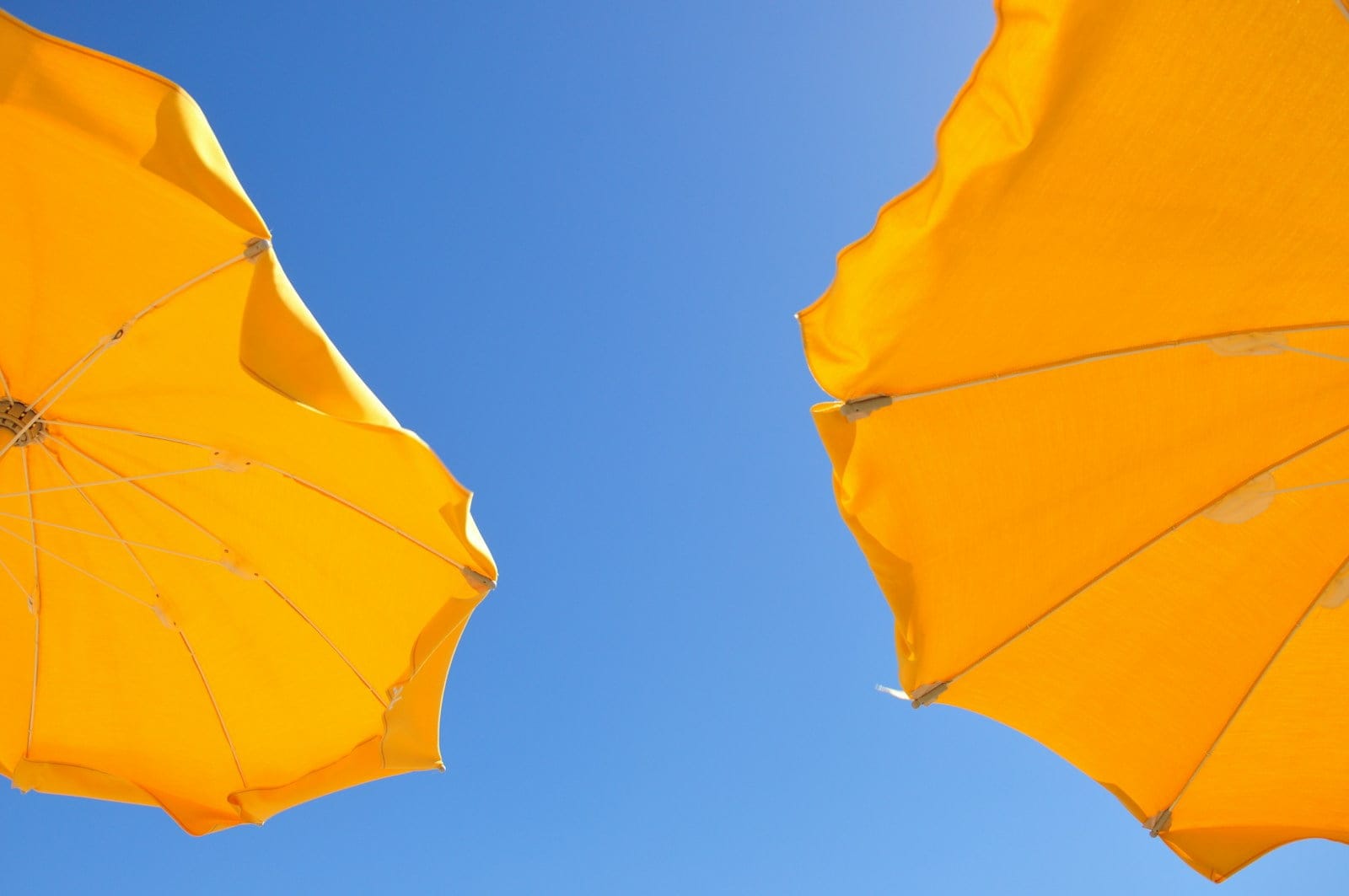 two yellow patio umbrellas under blue sky during daytime
