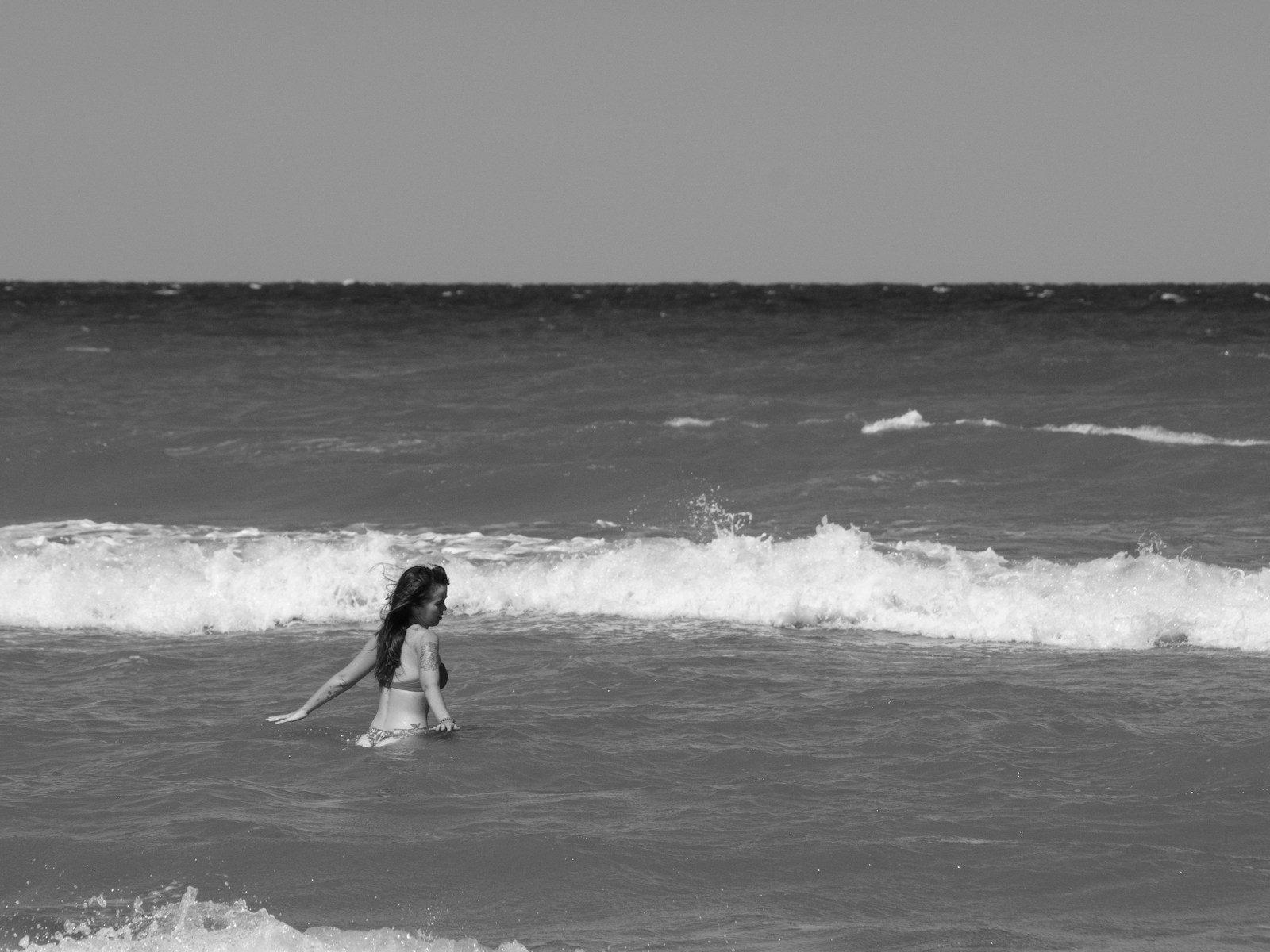 grayscale photo of woman surfing on sea waves
