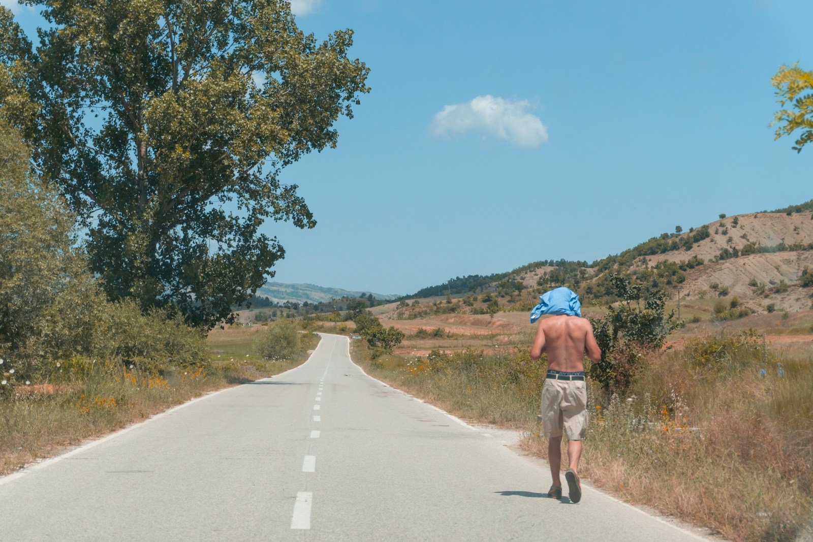 man in brown shirt and gray shorts riding bicycle on gray concrete road during daytime