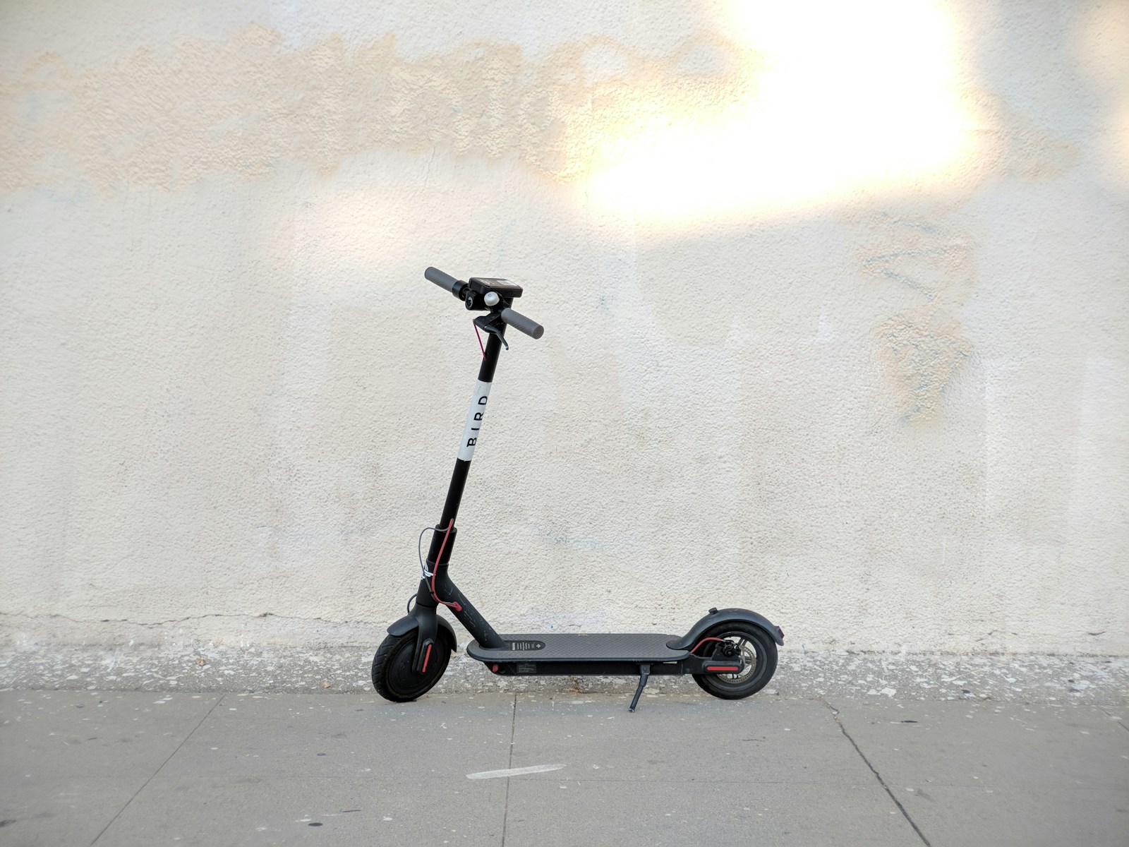 a scooter parked on a sidewalk next to a wall