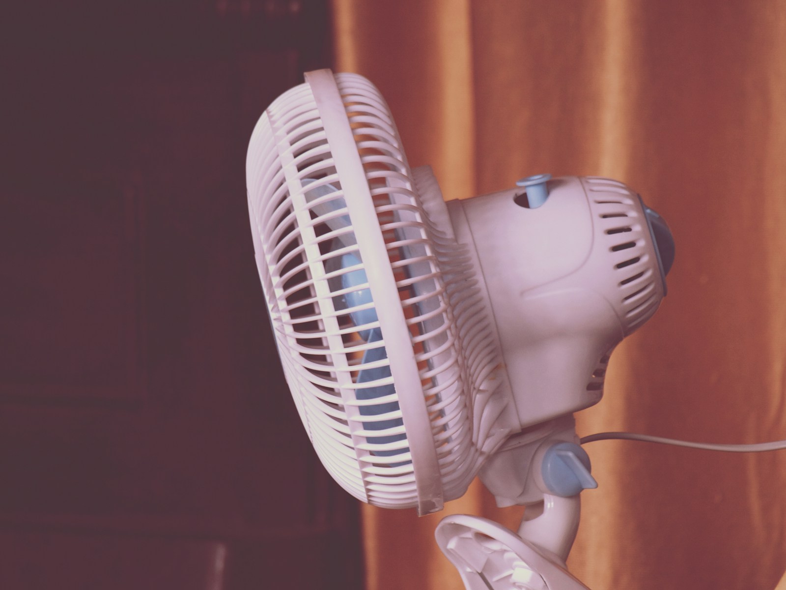 A white fan sitting on top of a window sill