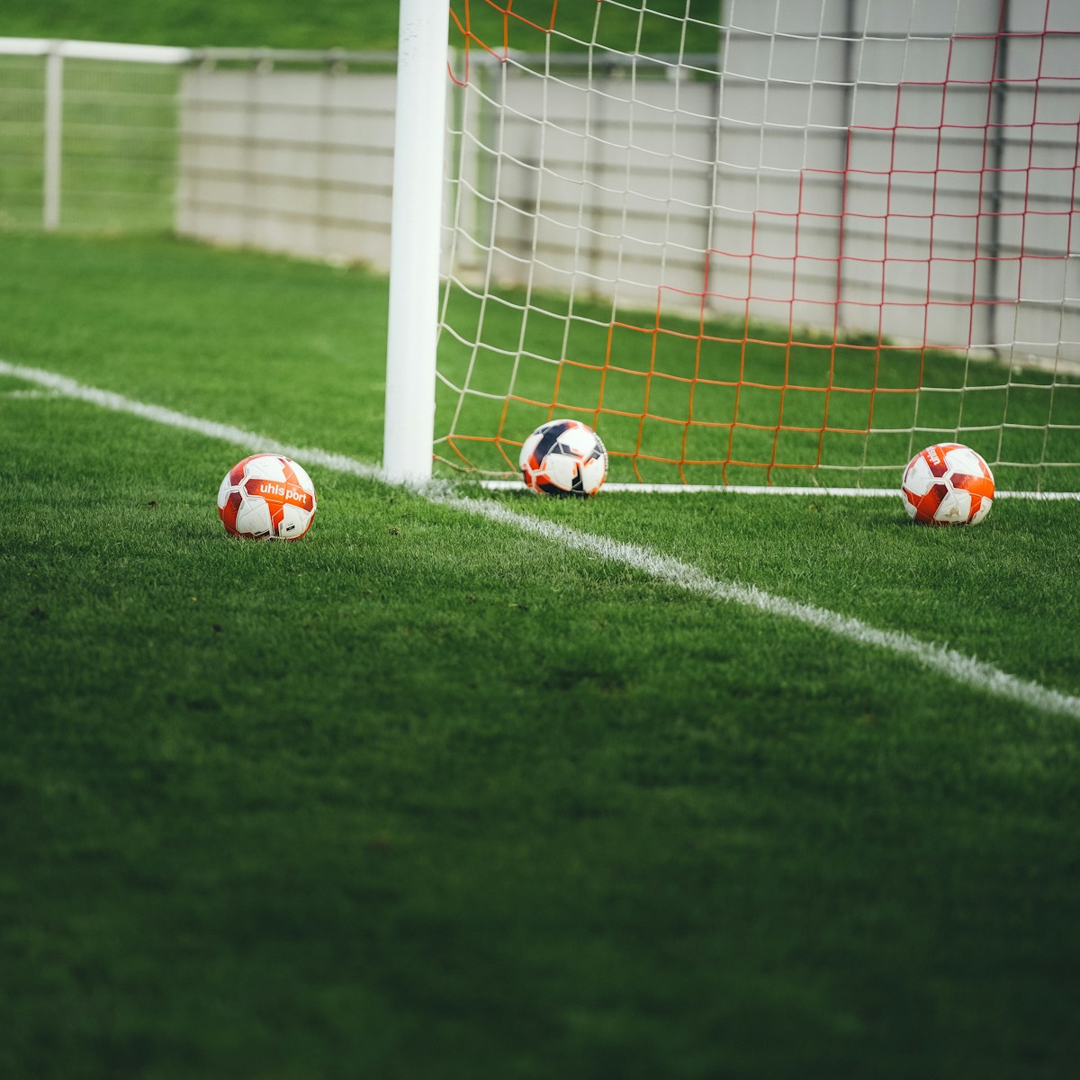 Three soccer balls near a goal net