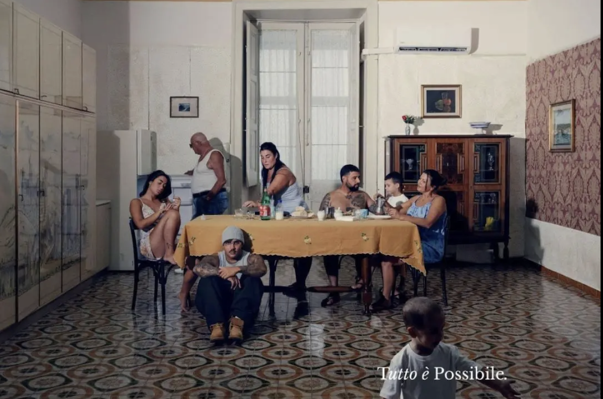 Geolier in Canzone d’amore, album Tutto è possibile, seduto sotto il tavolo in una scena di vita familiare