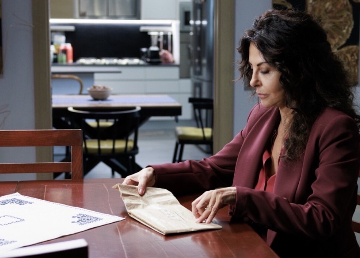 Sabrina Ferilli in A Testa Alta mentre apre una busta in una scena dell’ultima puntata