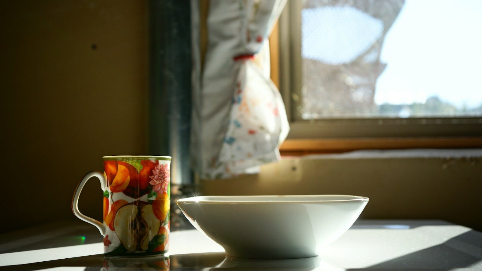 A coffee cup sitting on top of a table next to a window